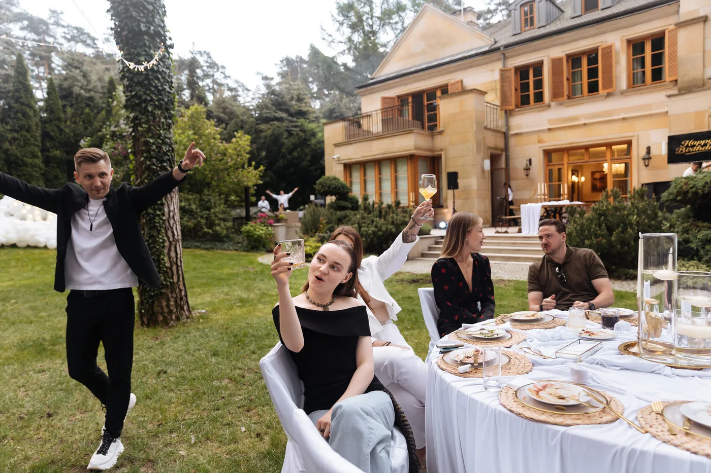 Guests at the celebration table in the garden beside a country house