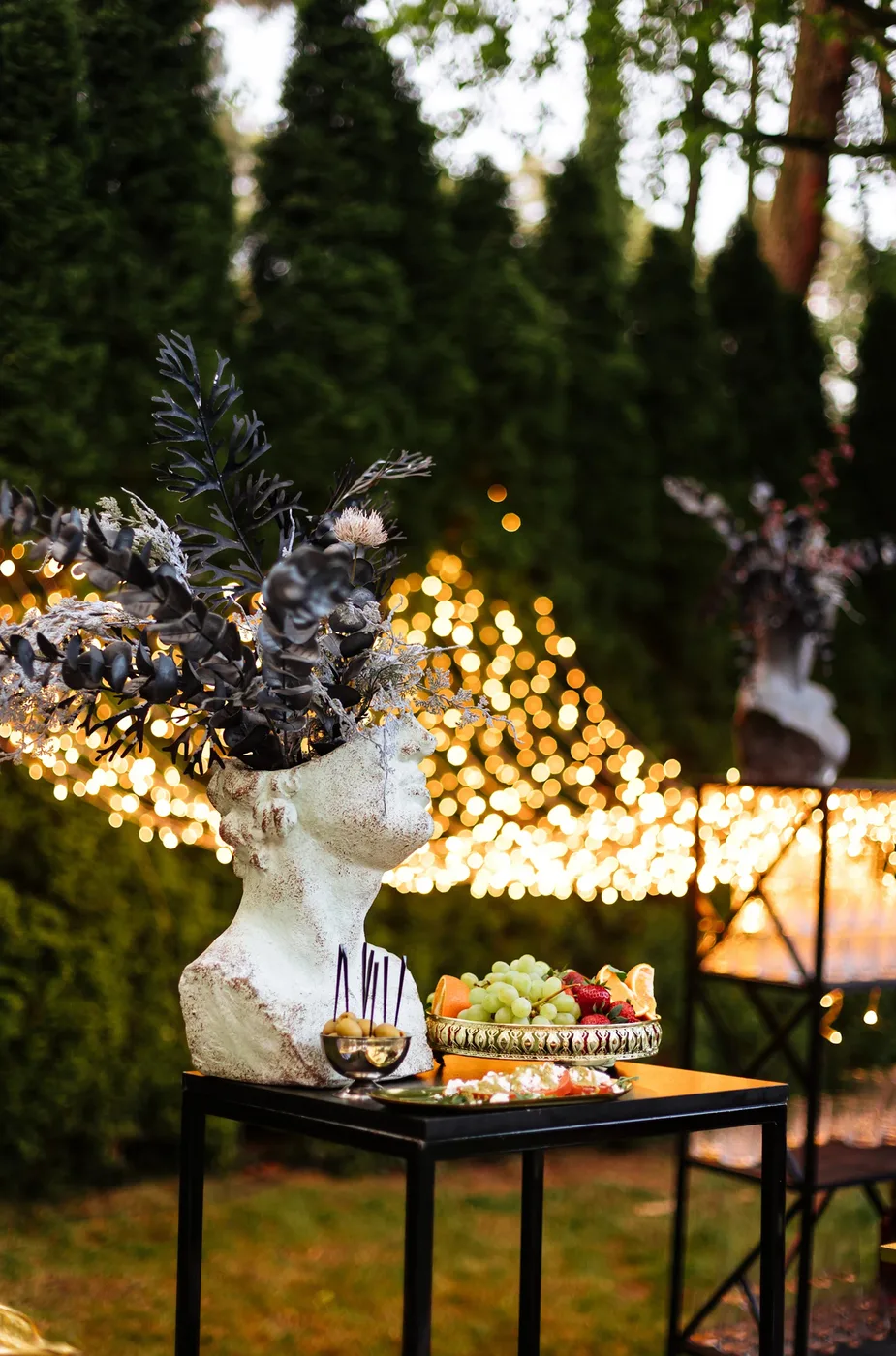 A decorative arrangement of fruit, olives and greenery against the lighting