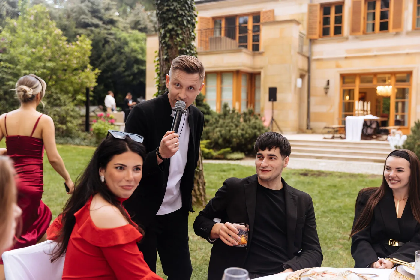 The host running an interactive segment with guests in front of the country house