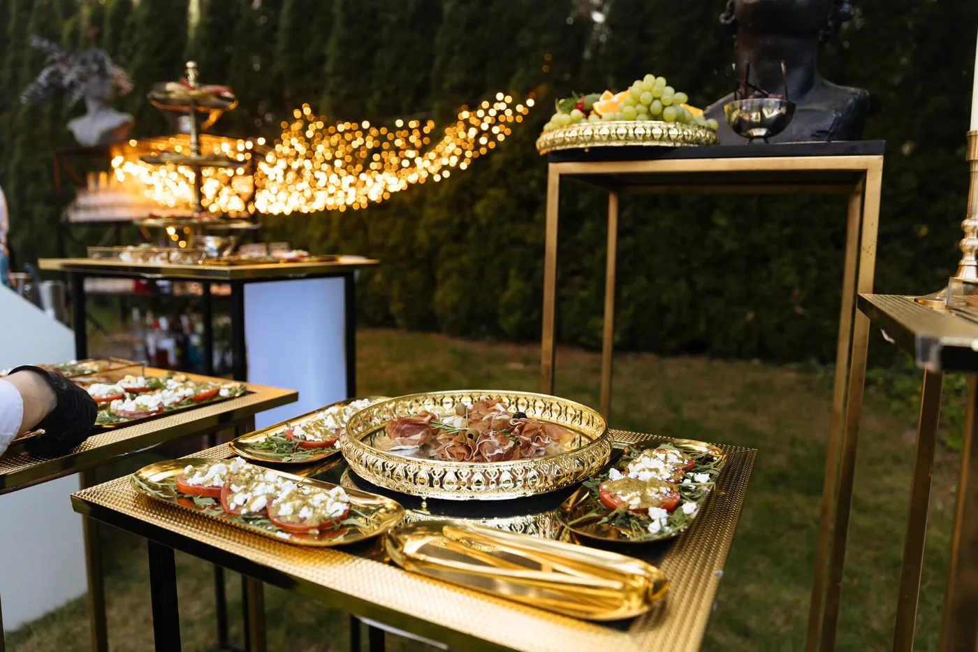 Italian appetisers on gold trays: prosciutto, tomatoes with cheese and fruit