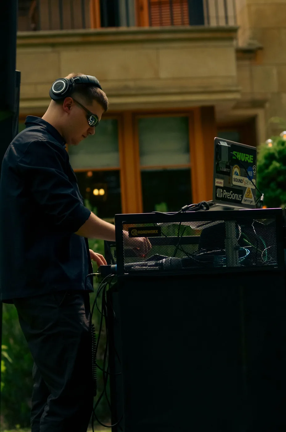 DJ przy konsoli pod gołym niebem na tle fasady willi podczas eventu firmowego