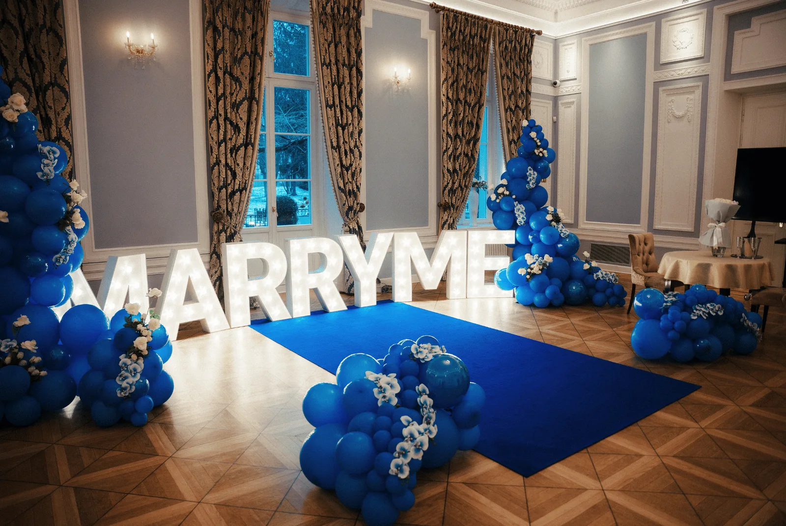 A styled Hotel Bellotto hall with illuminated 'MARRY ME' letters, flowers and candles