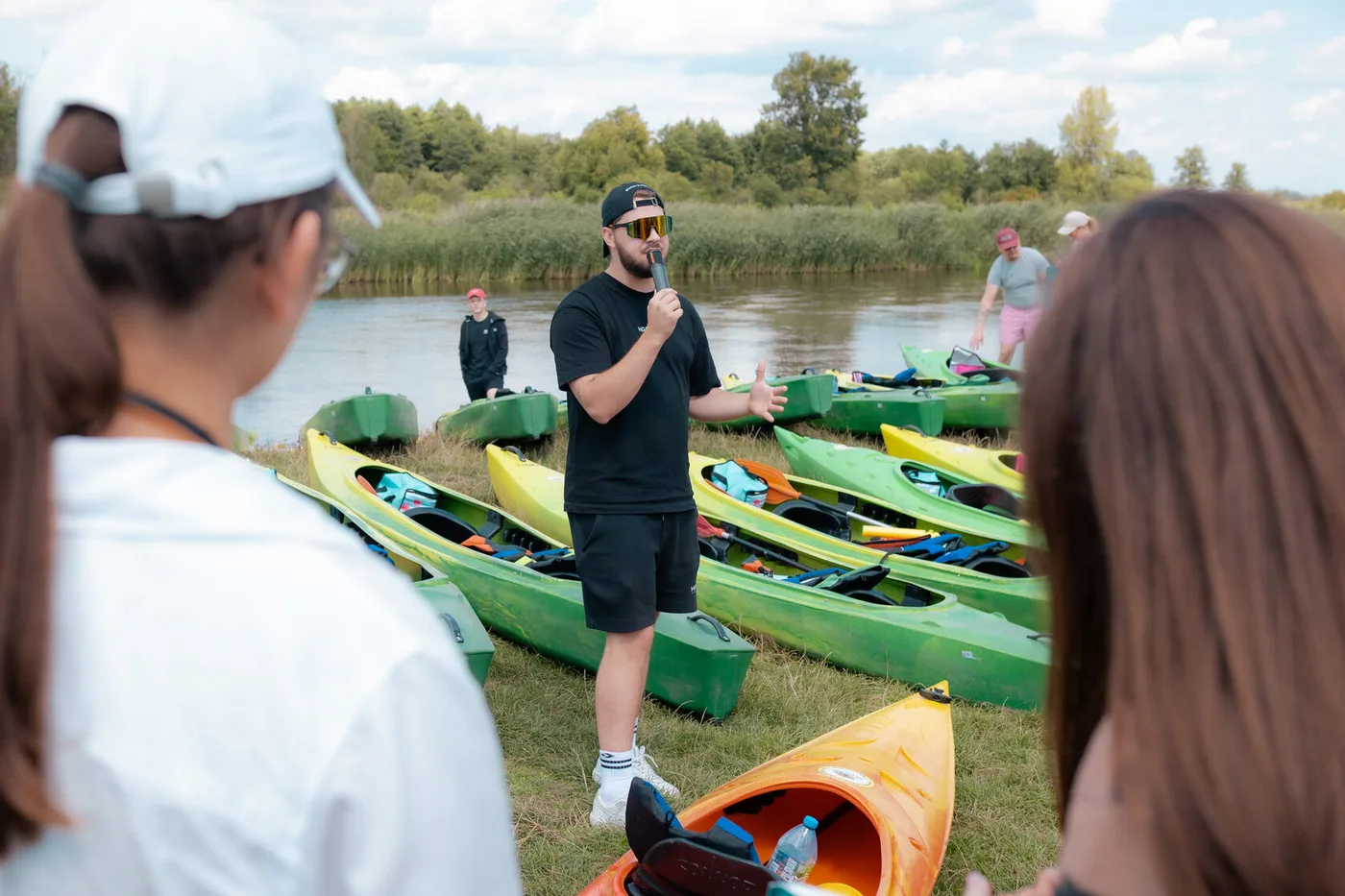 A briefing before the trip, beside the kayaks on the riverbank
