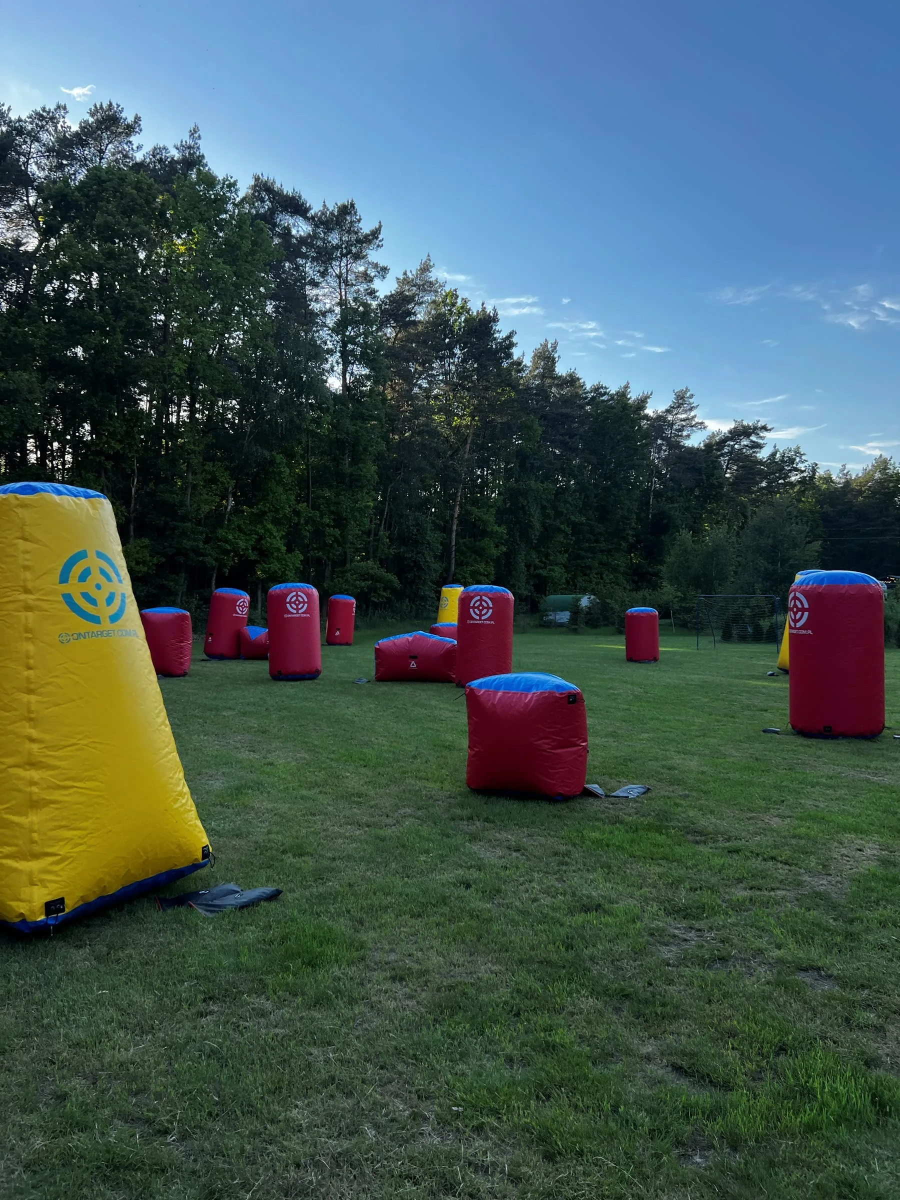 Inflatable game obstacles on a grassy field by a pine forest