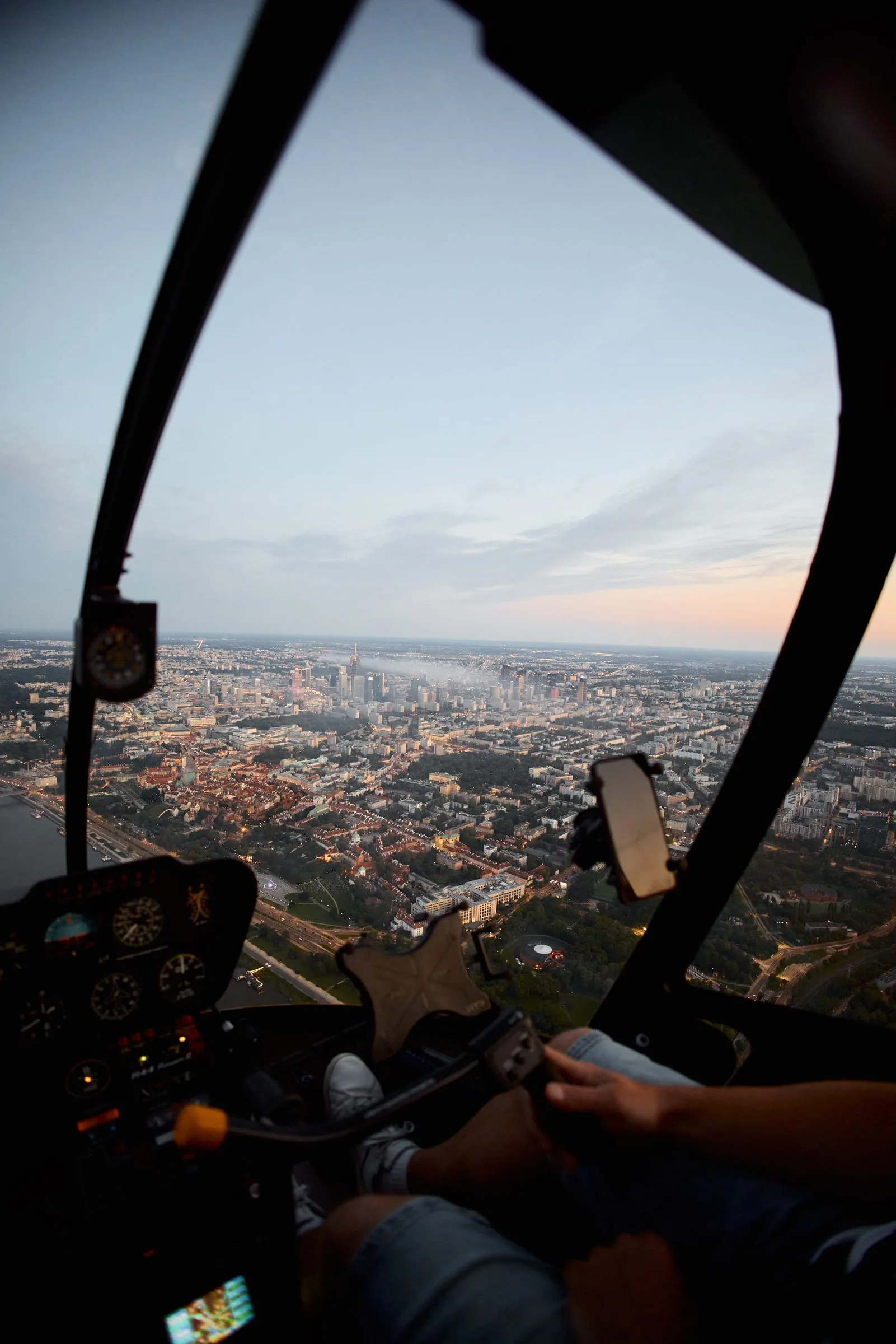 View from the helicopter cockpit during the flight: instrument panel, a hand on the controls and the city below