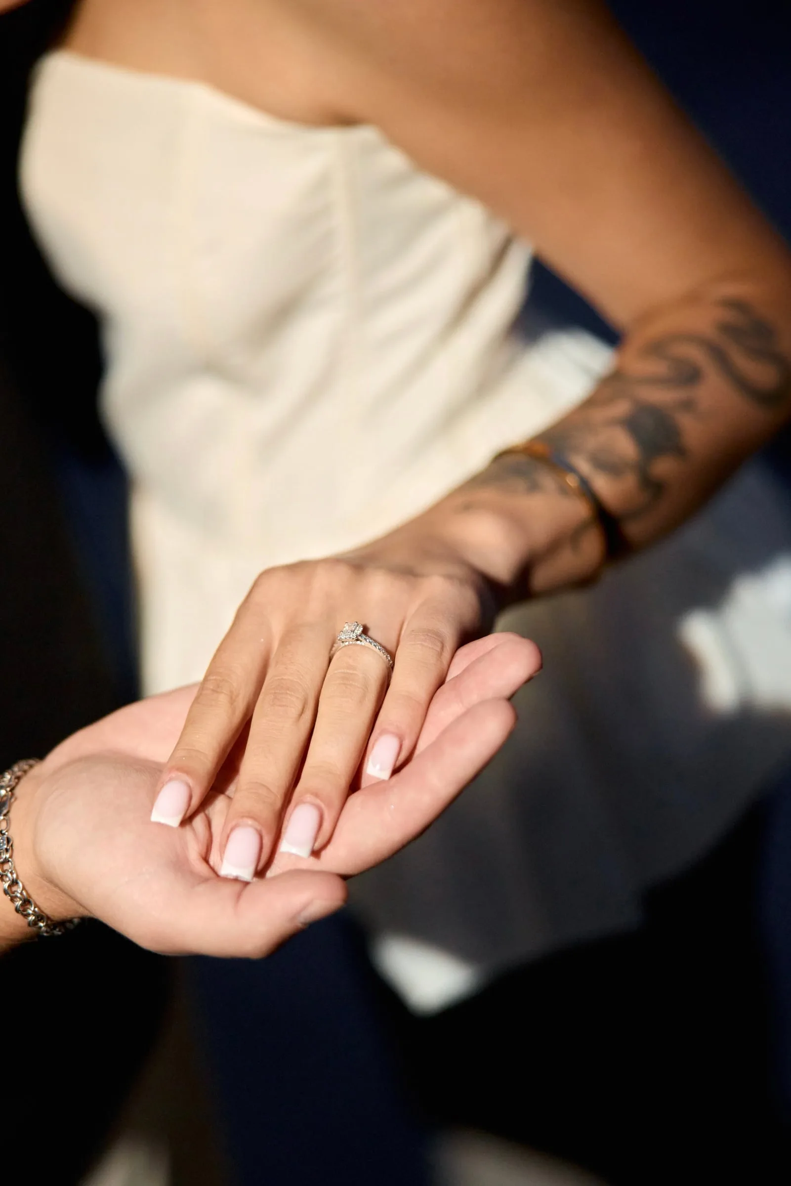 A woman’s hand with an engagement ring resting on a man’s palm