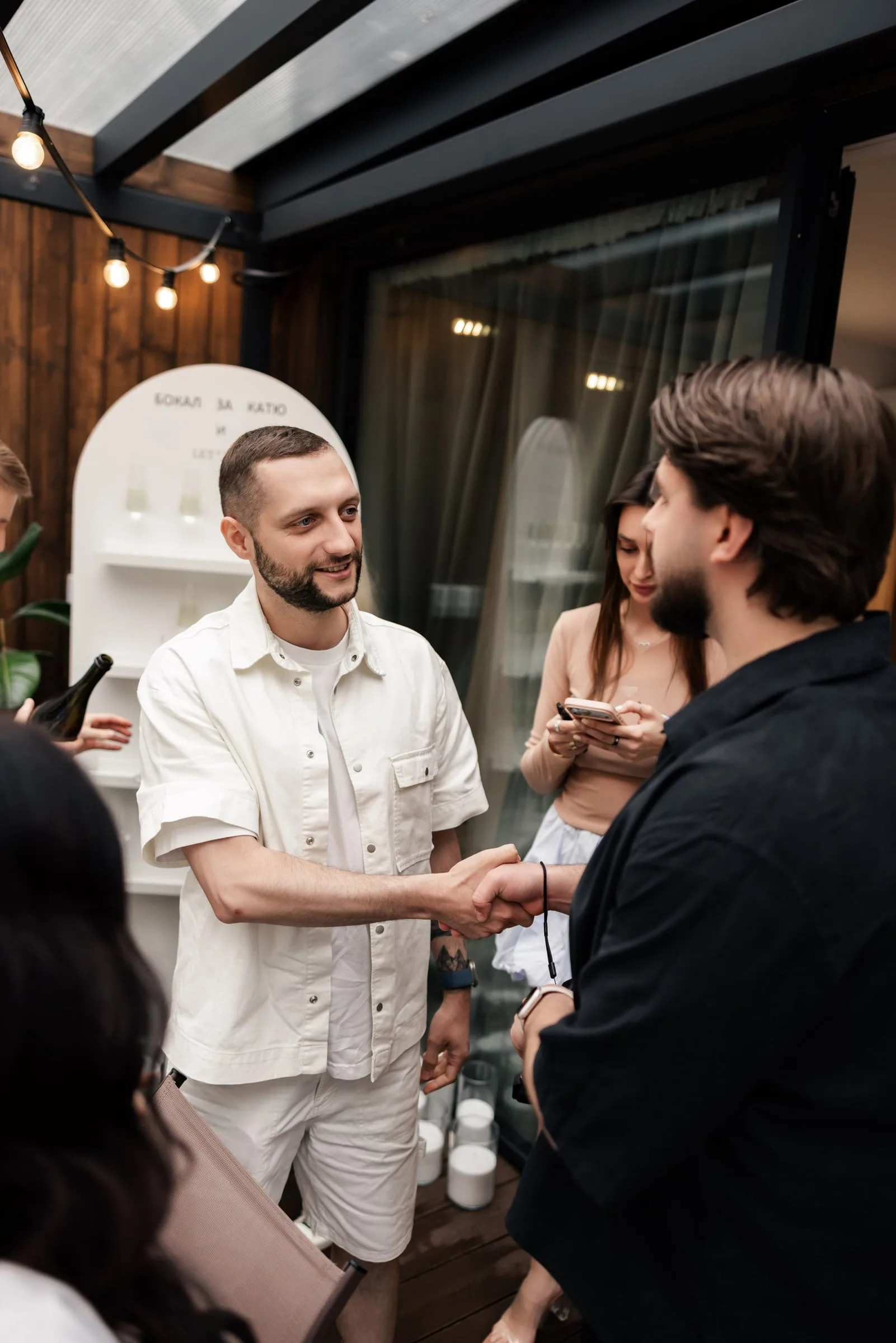 Makar shaking hands with a guest in a white shirt on the terrace