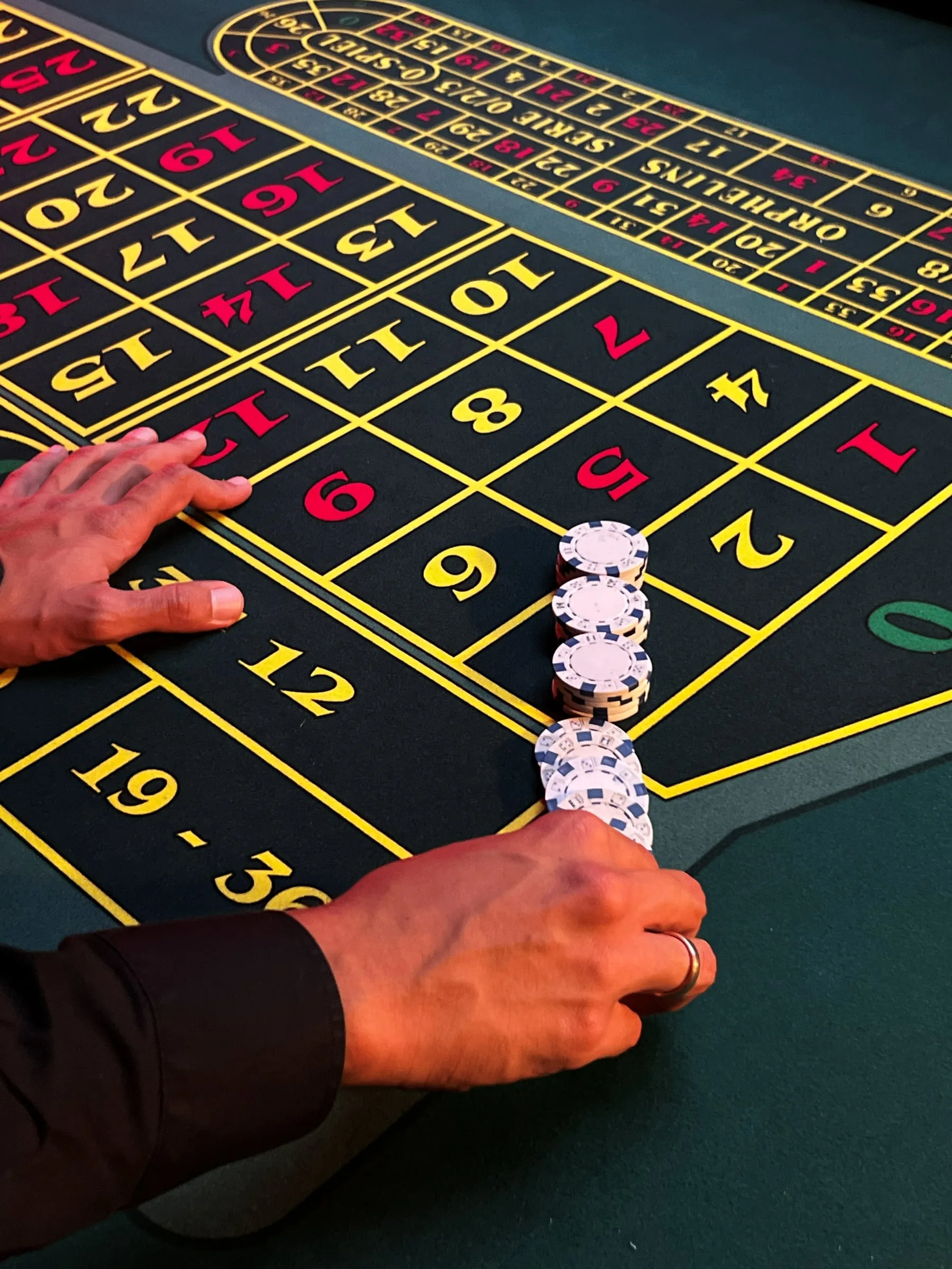 Smiling croupier at a roulette table with a marked roulette layout